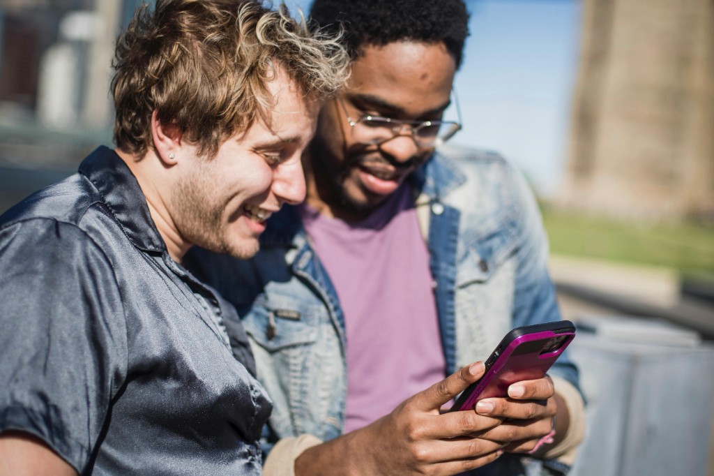 Friends looking at a phone together outdoors