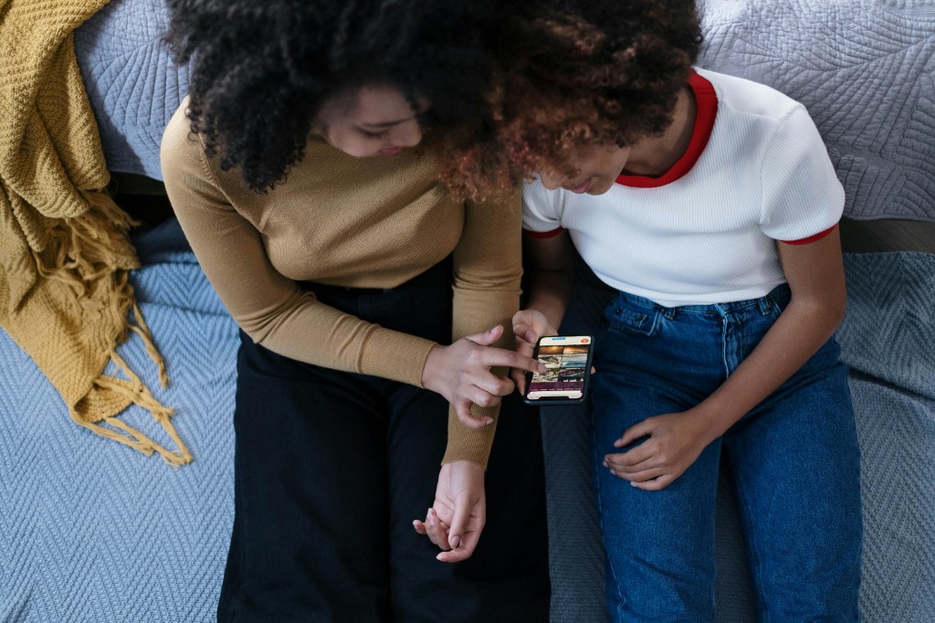 Two people sitting together on the floor, looking at a smartphone screen